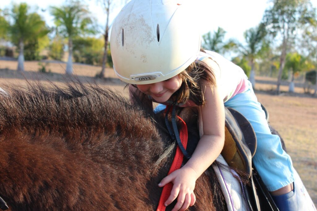 Girl in Blue Pants Riding Brown Animal